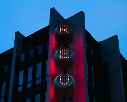 Urban Beacon A tall modern building features a vertical row of glowing red circular lights against a blue evening sky, creating a futuristic architectural look.