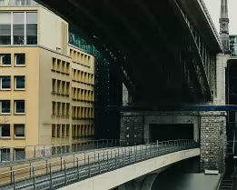 Urban Layers Yellow office block meets the underside of an elevated bridge in a layered city scene.