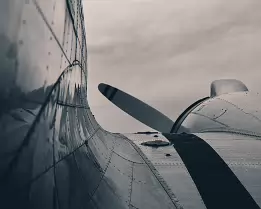 Riveted Grace A close-up shows the curved body and rivets of a vintage propeller plane.