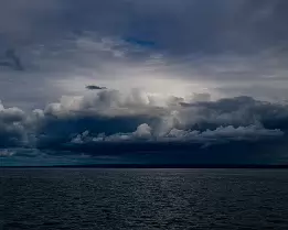 Moody Sky Dramatic storm clouds loom over a dark lake under a dim sky.