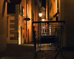 Alley of Echoes A lone shopping cart stands in a quiet alley, lit only by warm streetlamps. A strange, quiet moment in the heart of the city.