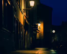 The Lantern Path A narrow street glows under warm lanterns, their light tracing the old facades and wet cobblestones. The deep blue sky and distant clock hint at a quiet city...